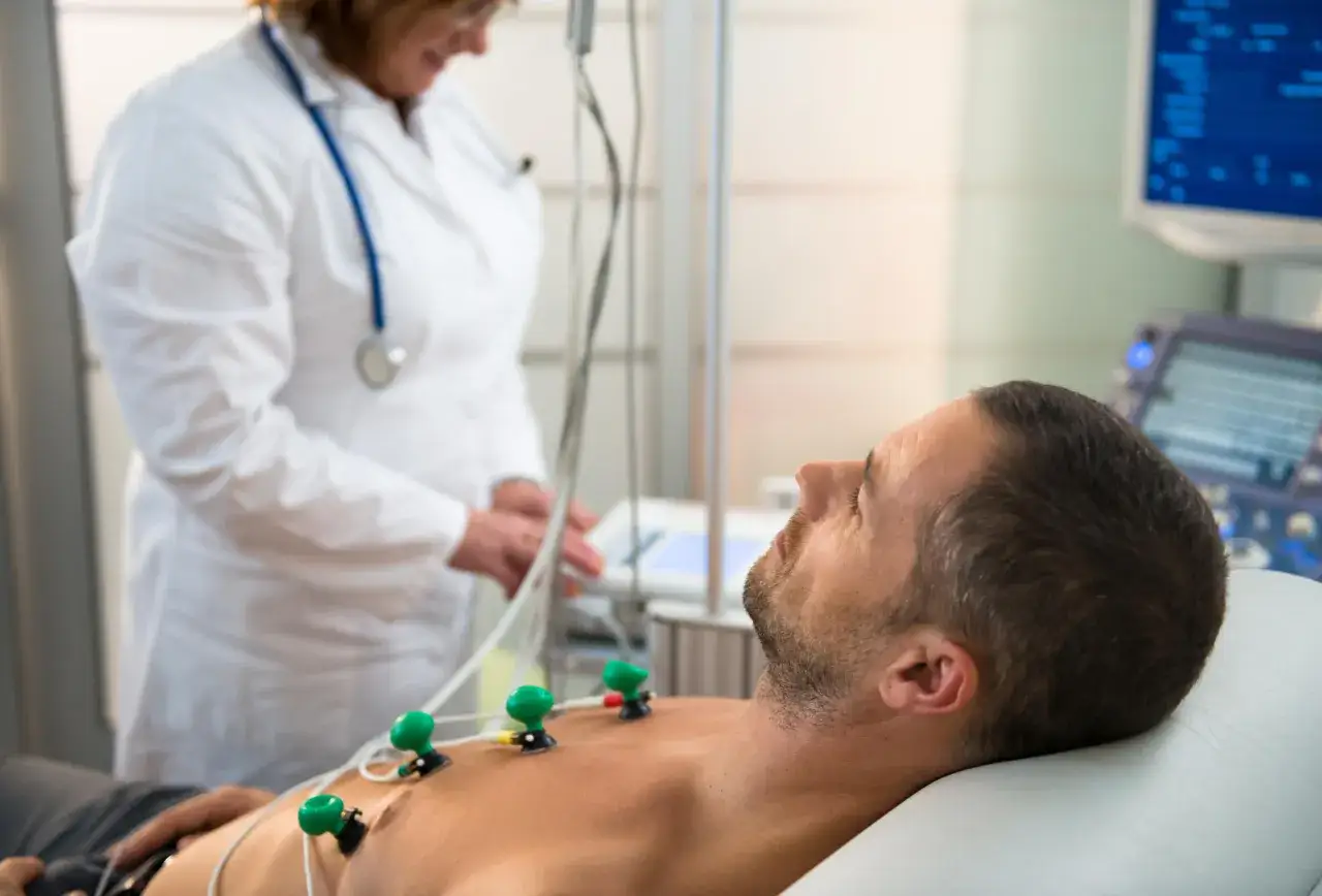 Pacjent z elektrodami EKG na klatce piersiowej, lekarz monitoruje jego stan. Badanie może pomóc dobrać lek na obniżenie tętna.
