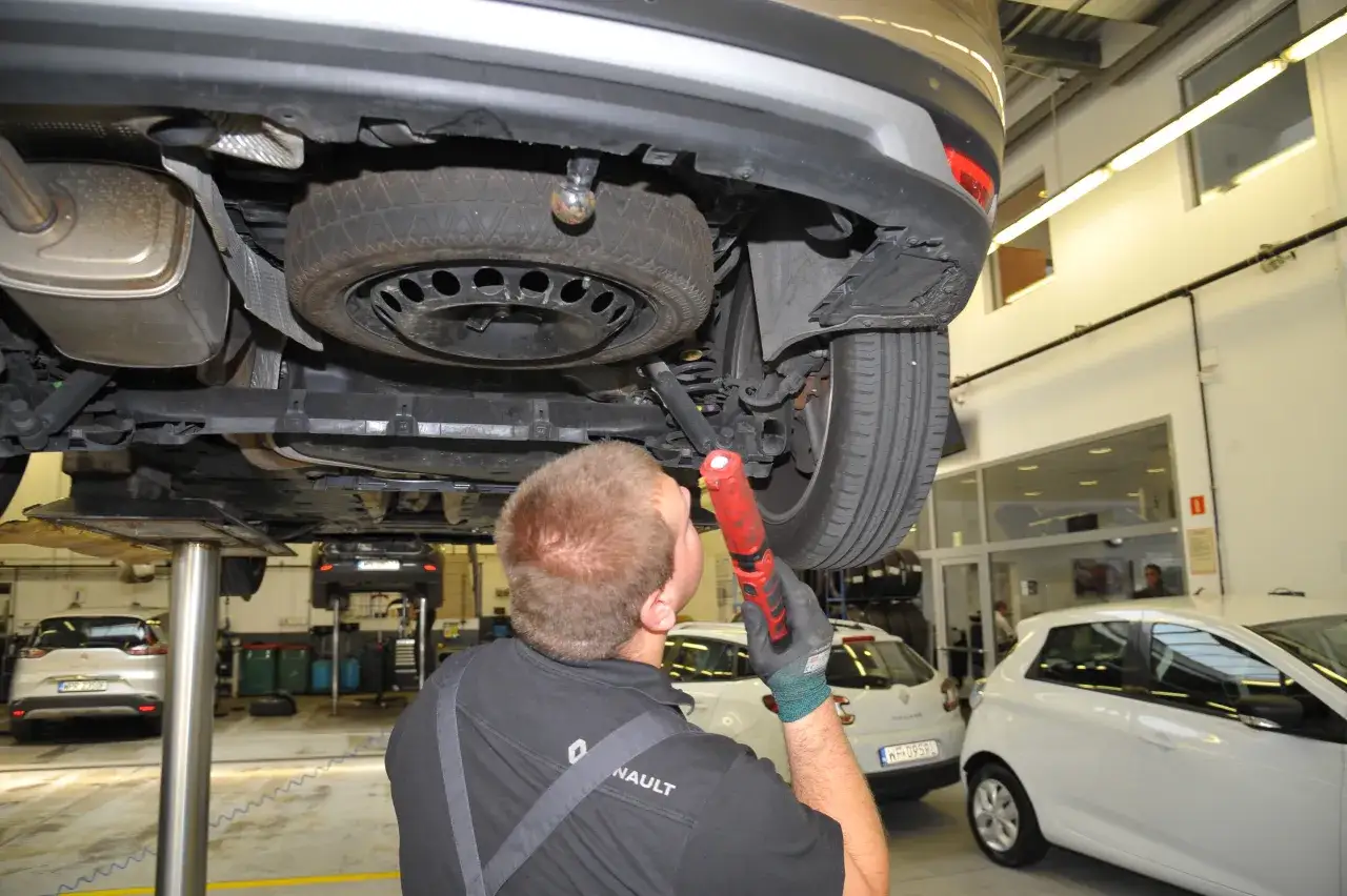 Mechanik szuka przyczyny głuchego stukania podczas jazdy, sprawdzając podwozie samochodu.