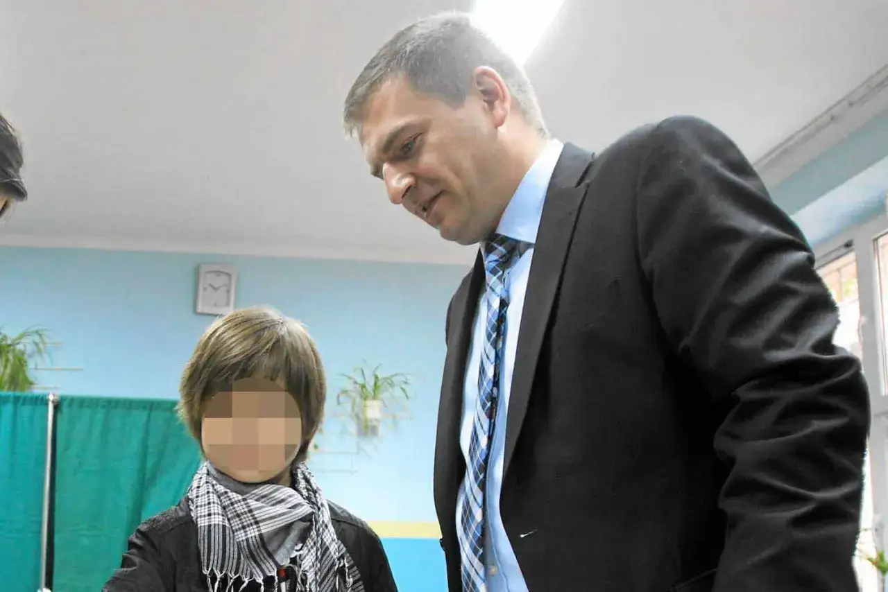 Bartosz Arłukowicz pochyla się nad dzieckiem, rozmawiając z nim.