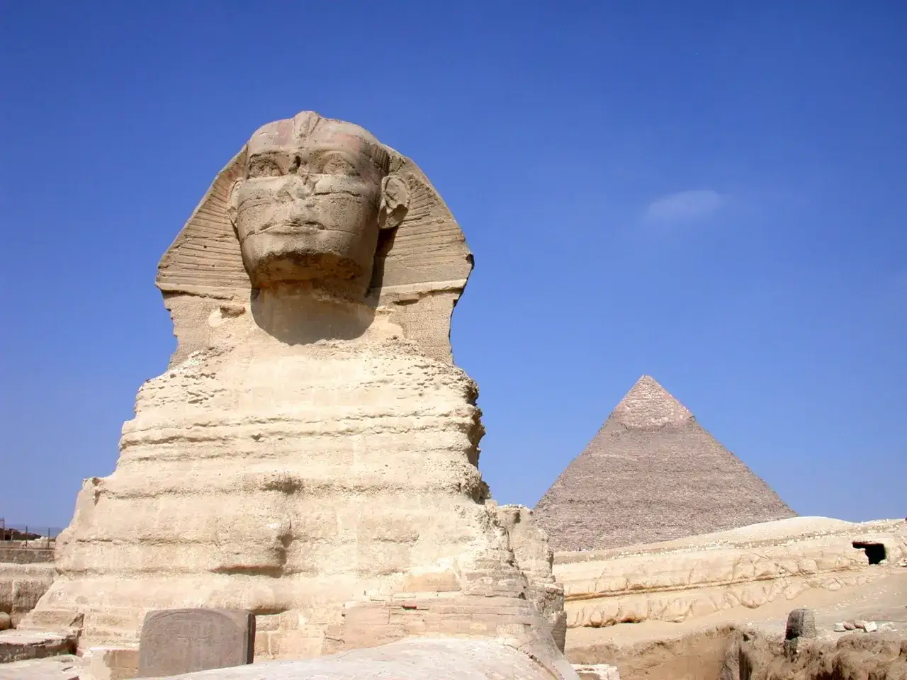 La Gran Esfinge y una pir&aacute;mide, ic&oacute;nicos monumentos que ver en Egipto, bajo un cielo azul intenso.