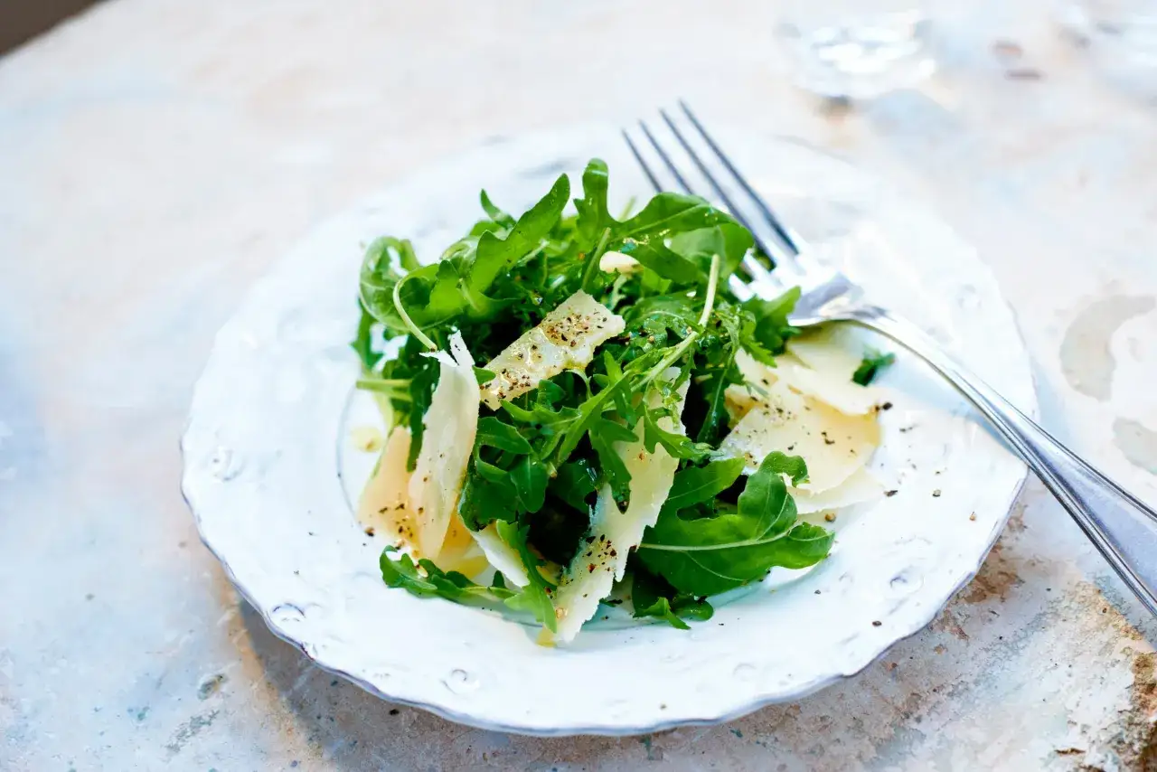 En fr&auml;sch sallad med ruccola och tunna flagor av parmesanost, kryddad med svartpeppar.