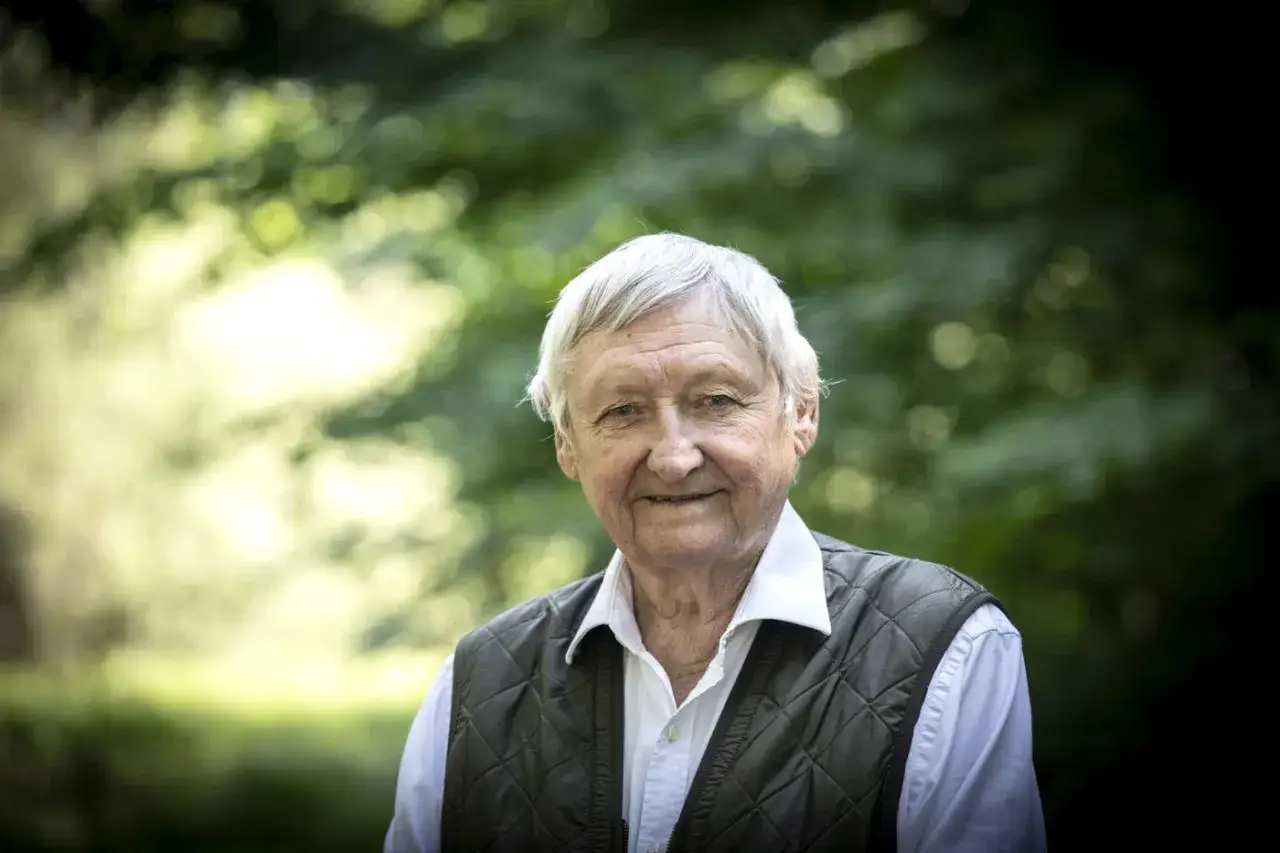 Äldre man med vitt hår, klädd i väst och skjorta, ler mot kameran. Kanske en av Ragnar Skanåkers barn?