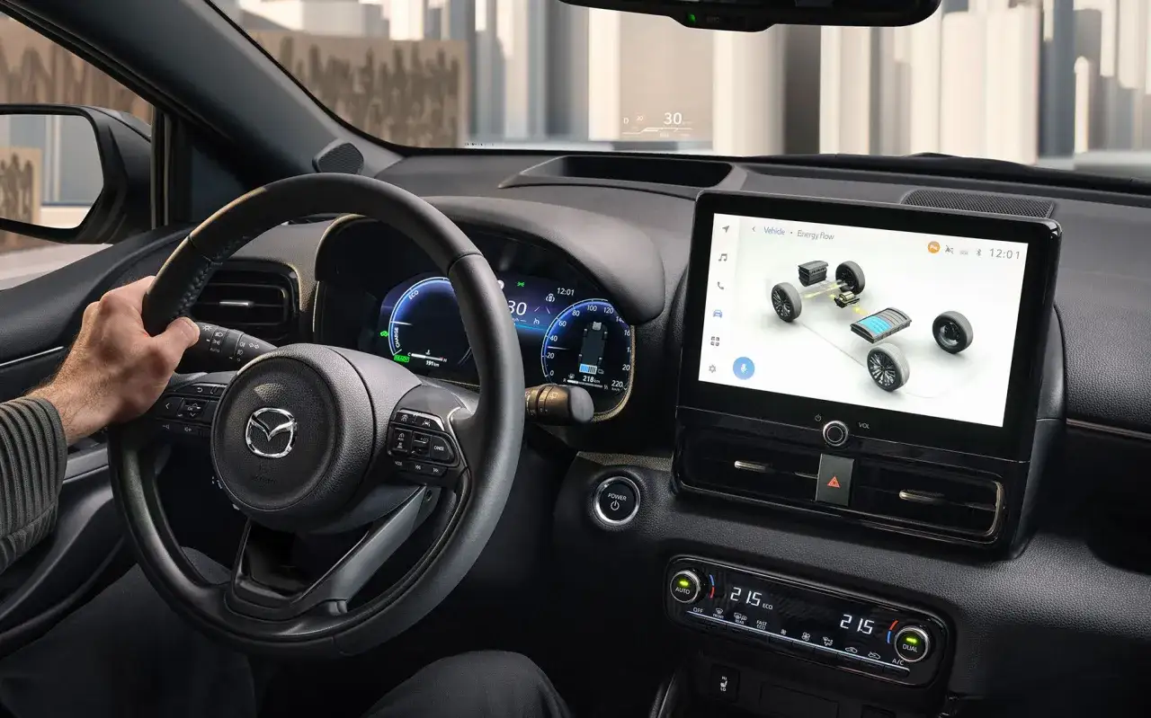Interior de un coche híbrido automático. Se ve el volante, la pantalla táctil mostrando el flujo de energía y el panel de control.
