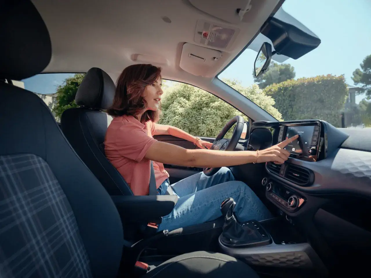 Kobieta dotyka ekranu nawigacji w Hyundai i10. Sprawdza aktualną hyundai i10 cena, planując podróż.