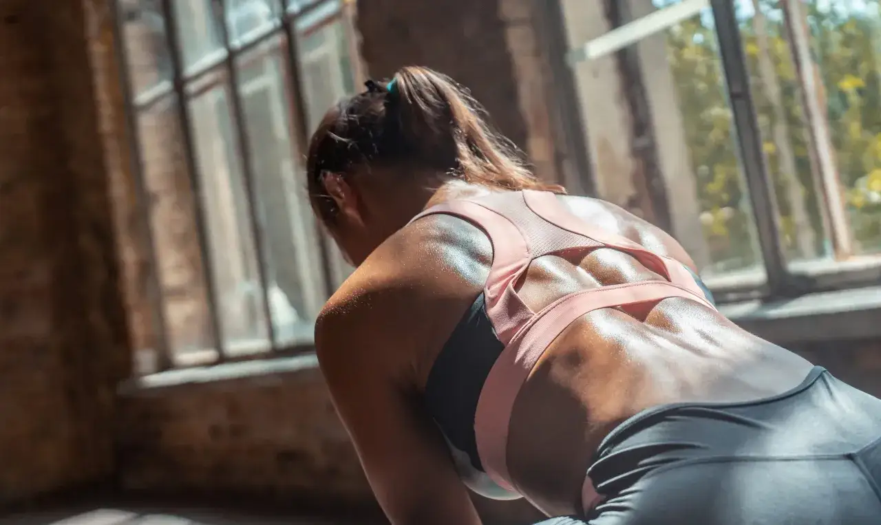 Donna sudata con muscoli lombari definiti, in posa dopo un allenamento intenso.