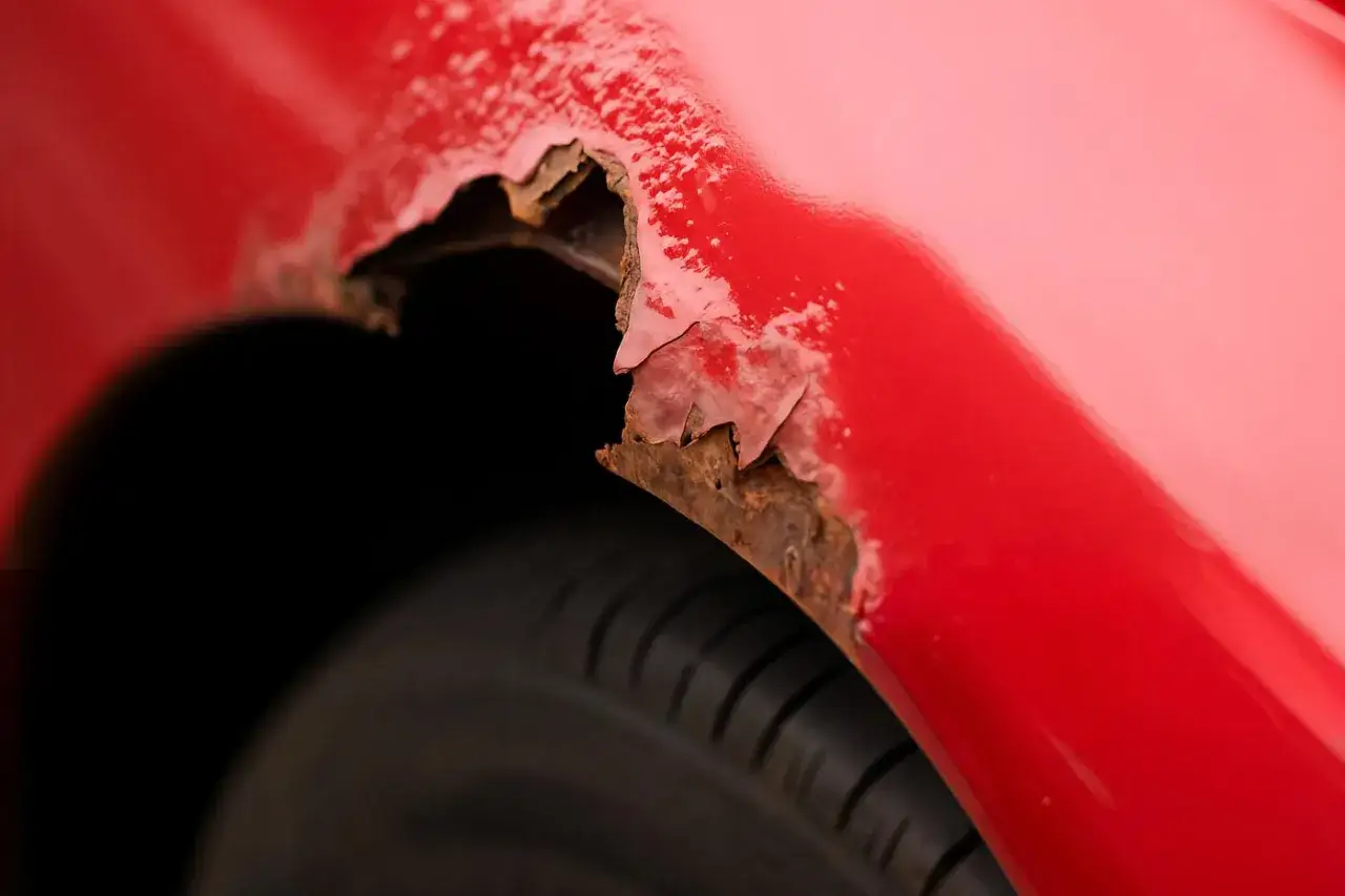 El &oacute;xido se ha apoderado del guardabarros de un coche rojo, mostrando el da&ntilde;o de un coche golpe.