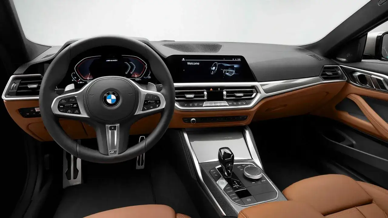 Wnętrze BMW G22 z brązową skórzaną tapicerką, nowoczesnym cyfrowym kokpitem i ekranem multimedialnym.