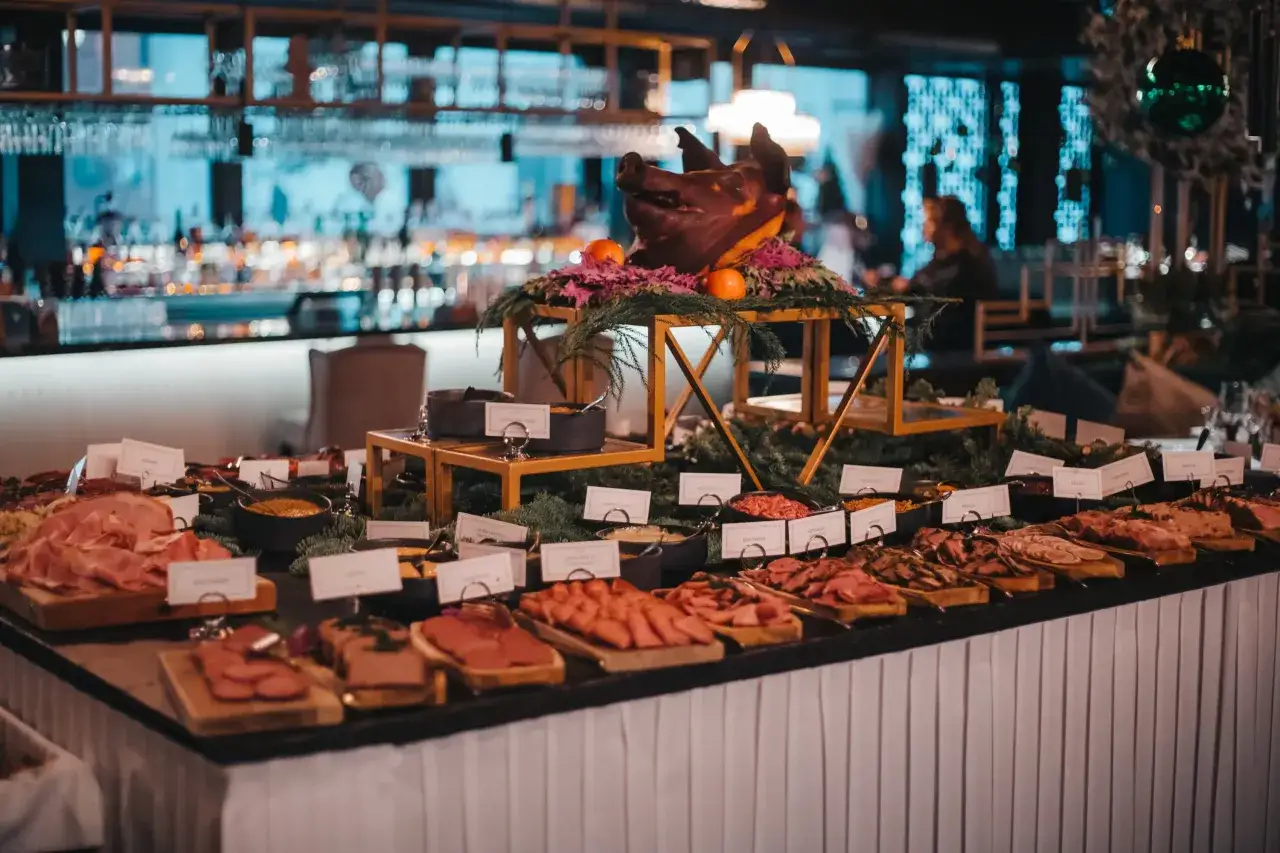 Ett dignande julbord med charkuterier, en dekorerad grisbuk och en bar i bakgrunden. Mister French julbord bjuder på en festlig upplevelse.