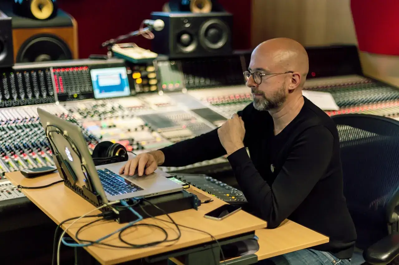 Hans Martin Buff sitzt an einem Mischpult, arbeitet am Laptop und h&ouml;rt Musik.