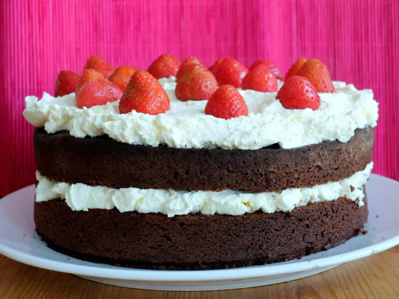 Pastel de chocolate de dos capas cubierto con crema batida y fresas frescas. ¡Una delicia irresistible!