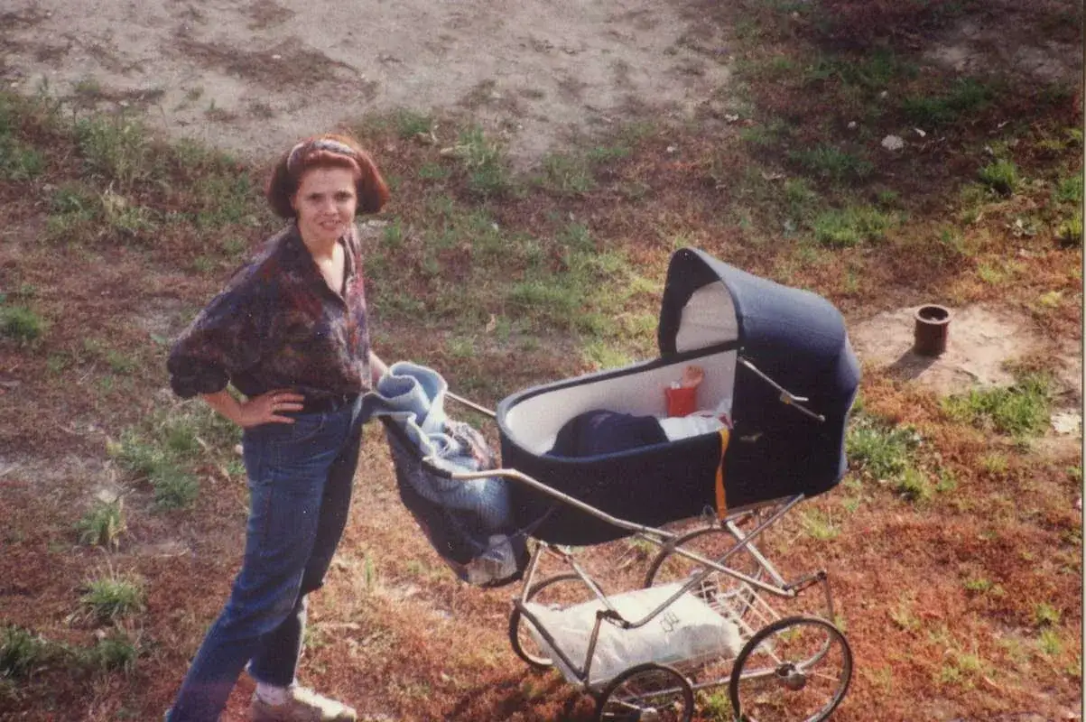 Kobieta z rudymi włosami i wózki dziecięce lata 90. na tle trawy.