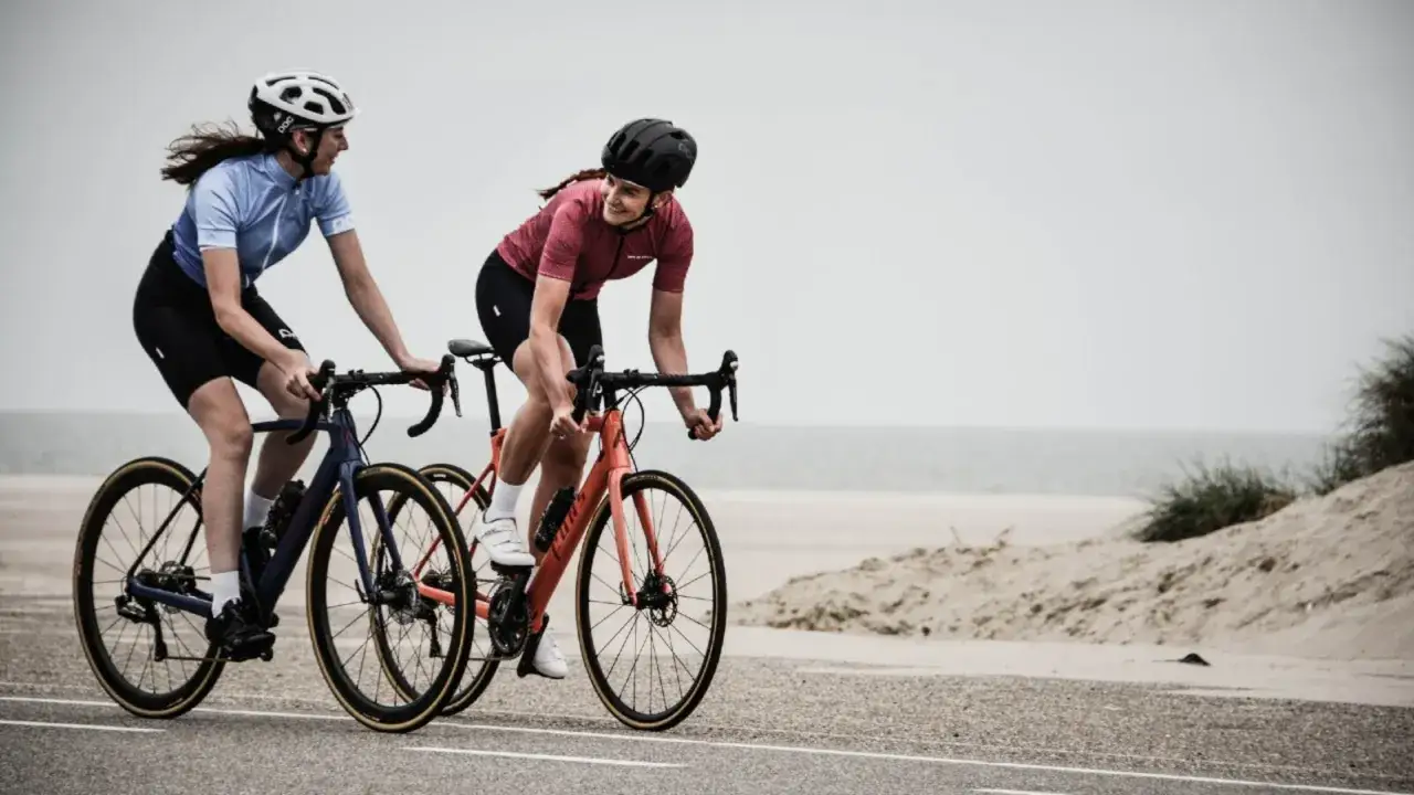 Dwie kobiety w kaskach i strojach kolarskich ścigają się rowerami wzdłuż plaży. Ile czasu zajmie im pokonanie 50 km na rowerze?