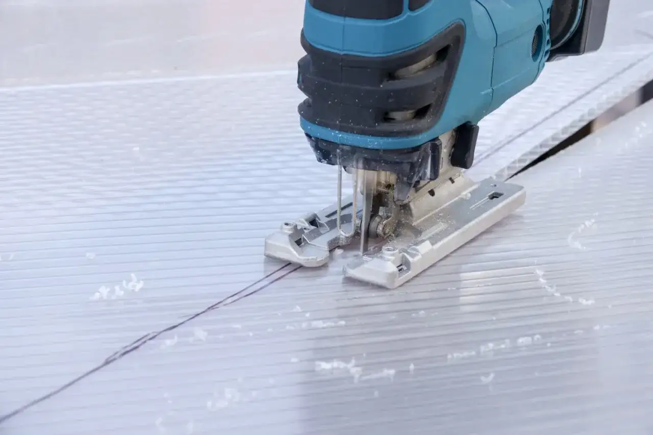 Mit einem Stichs&auml;geblatt werden Hohlkammerplatten pr&auml;zise geschnitten. Staubpartikel wirbeln auf, w&auml;hrend die S&auml;ge entlang der Markierung gleitet.
