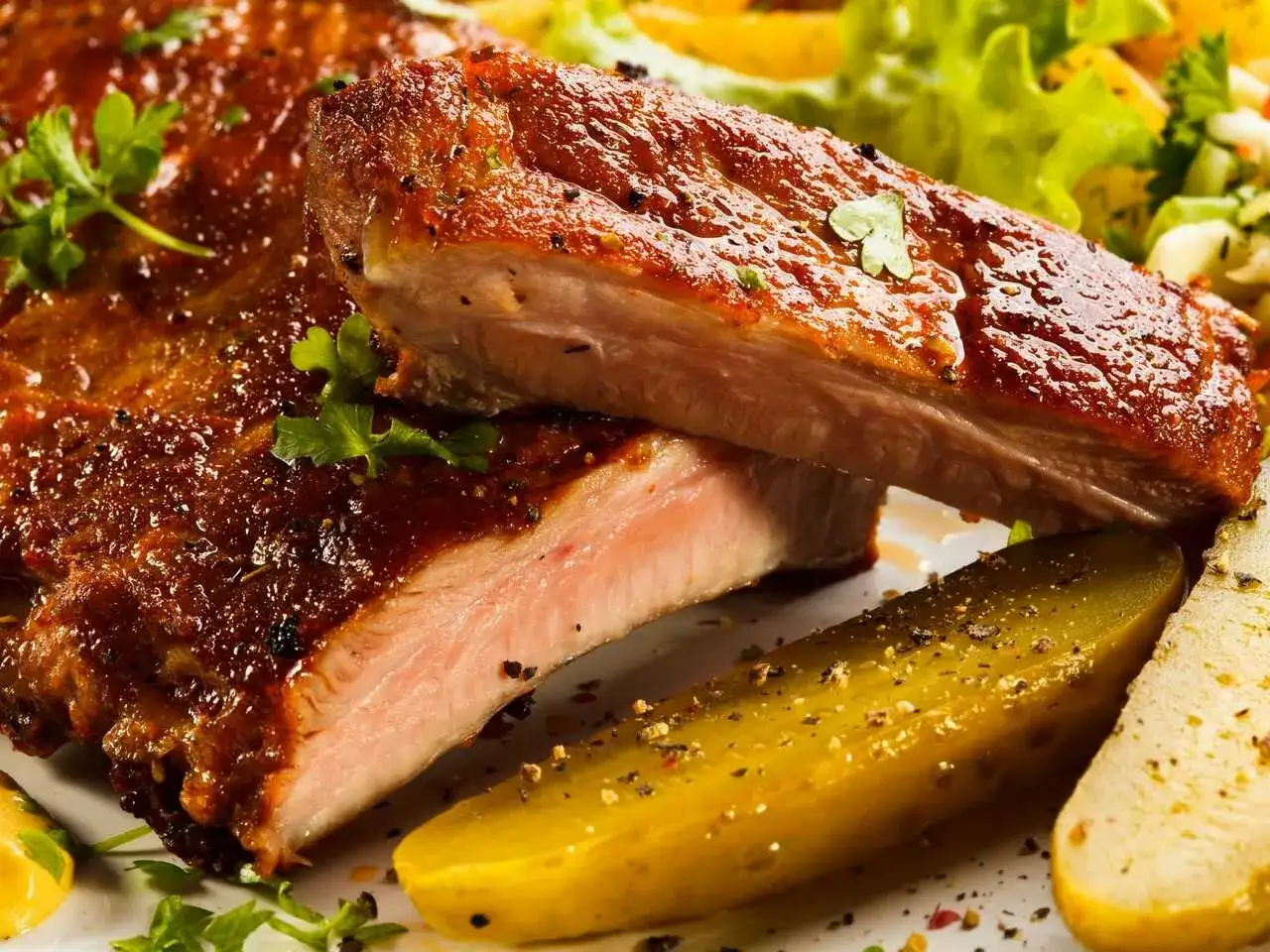 Costillas al horno con patatas, jugosas y doradas, acompa&ntilde;adas de ensalada fresca y pepinillos. &iexcl;Un fest&iacute;n para los sentidos!