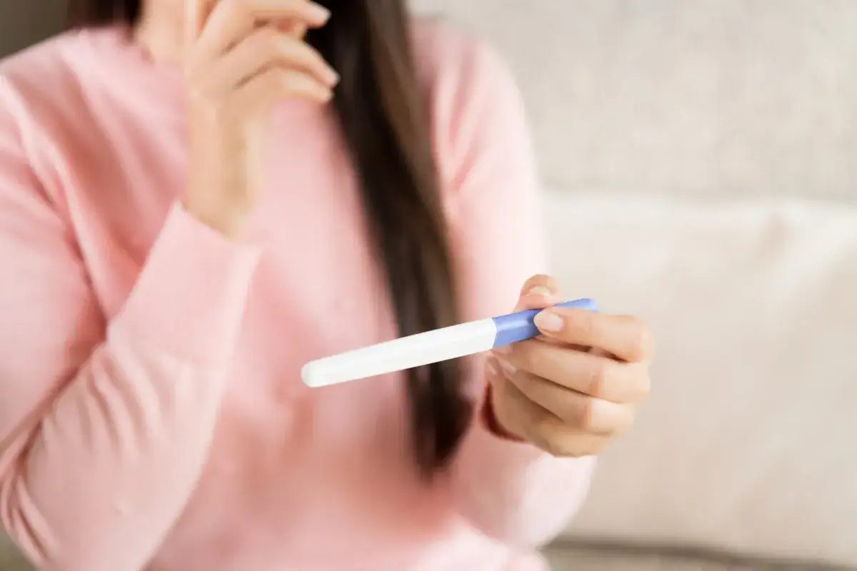 Kobieta z niepokojem trzyma test ciążowy, który może wskazywać na ciążę biochemiczną.