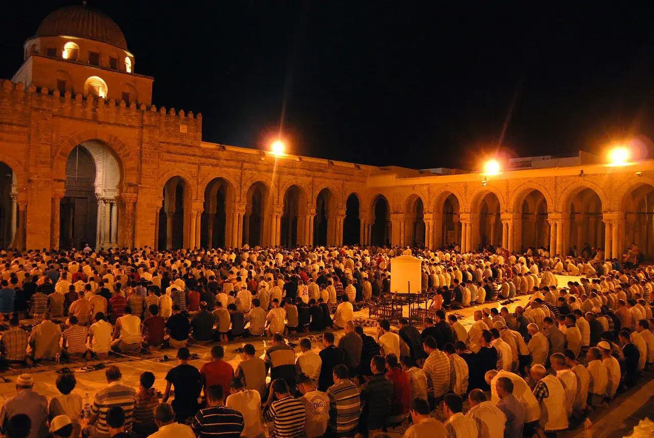 Große Menschenmenge betet nachts in einem Moscheehof. Dies erinnert an die Bedeutung von Laylatul Qadr, wie in Hadith erwähnt.