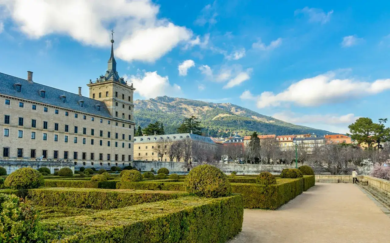 Ein perfekter tagesausflug madrid: das Kloster El Escorial mit seinen gepflegten G&auml;rten und dem majest&auml;tischen Bergpanorama im Hintergrund.