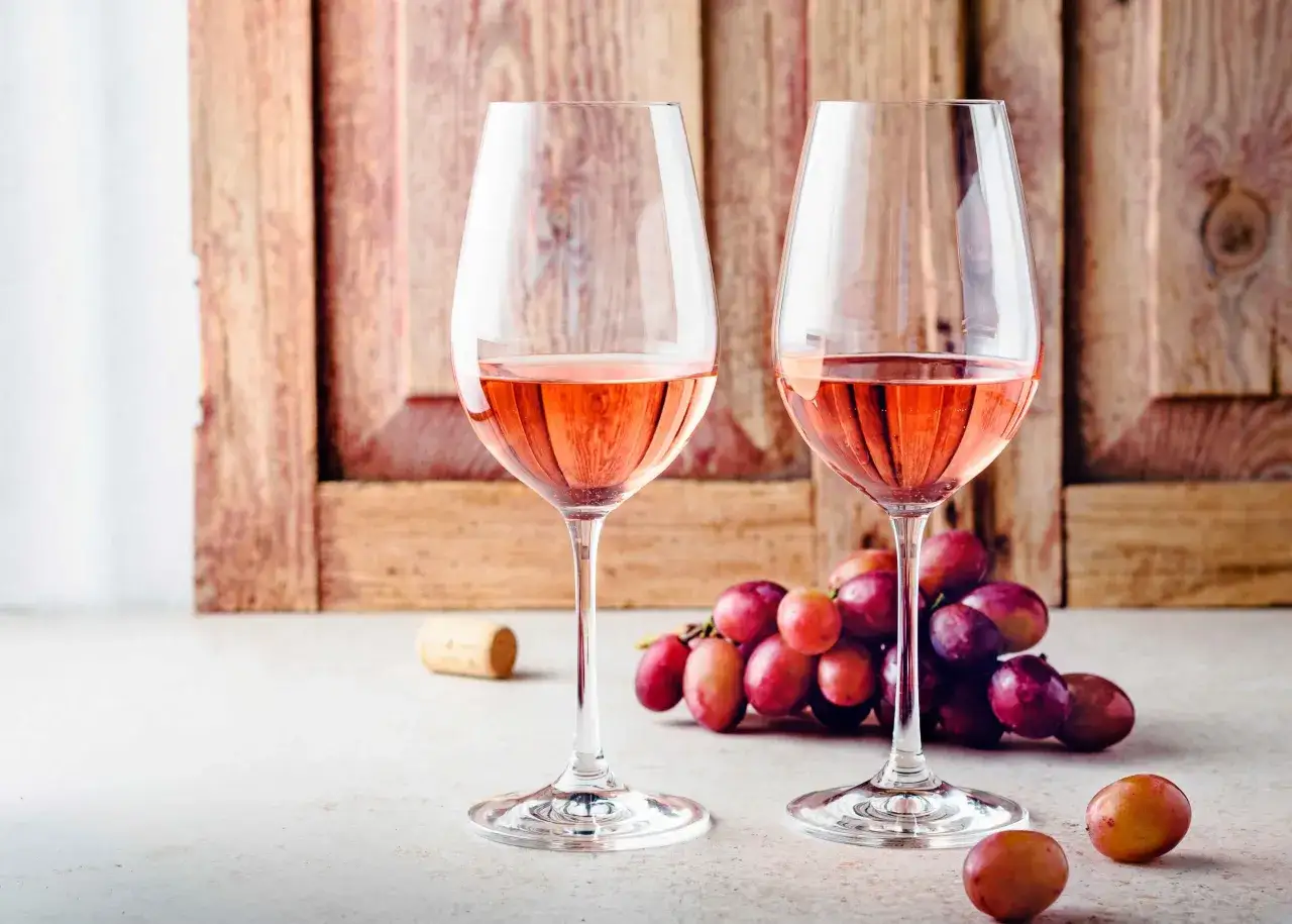 Dos copas de rosado, acompañadas de uvas y un corcho, evocan los mejores vinos de Cigales.
