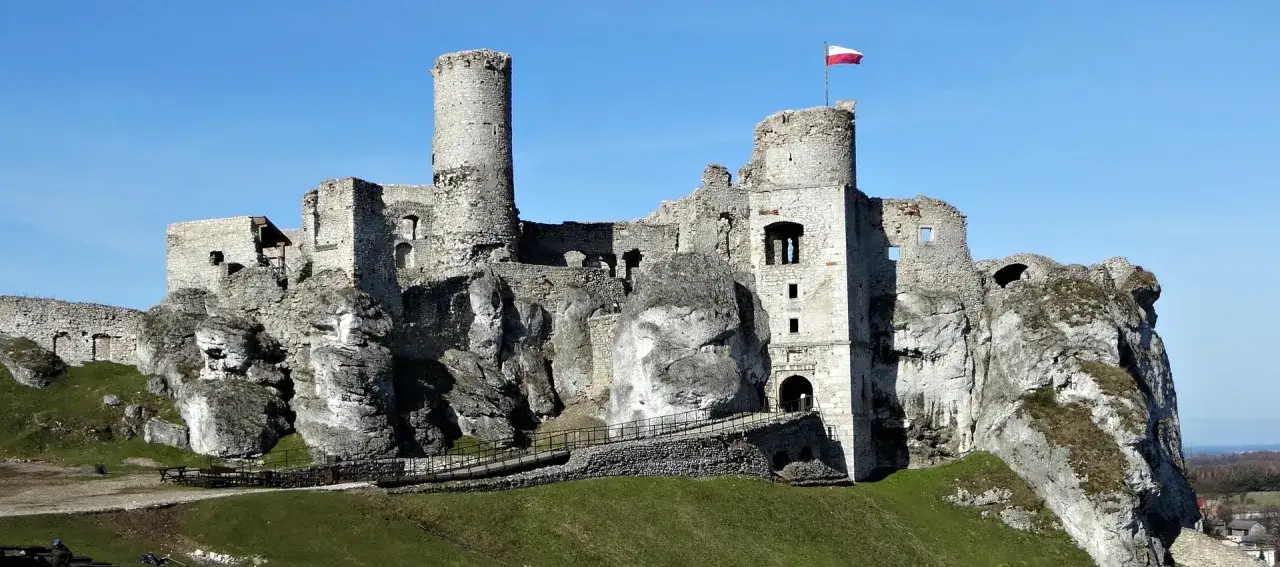 Ruiny zamku na skale, idealne na wycieczkę jednodniową. Polska flaga powiewa na wieży.