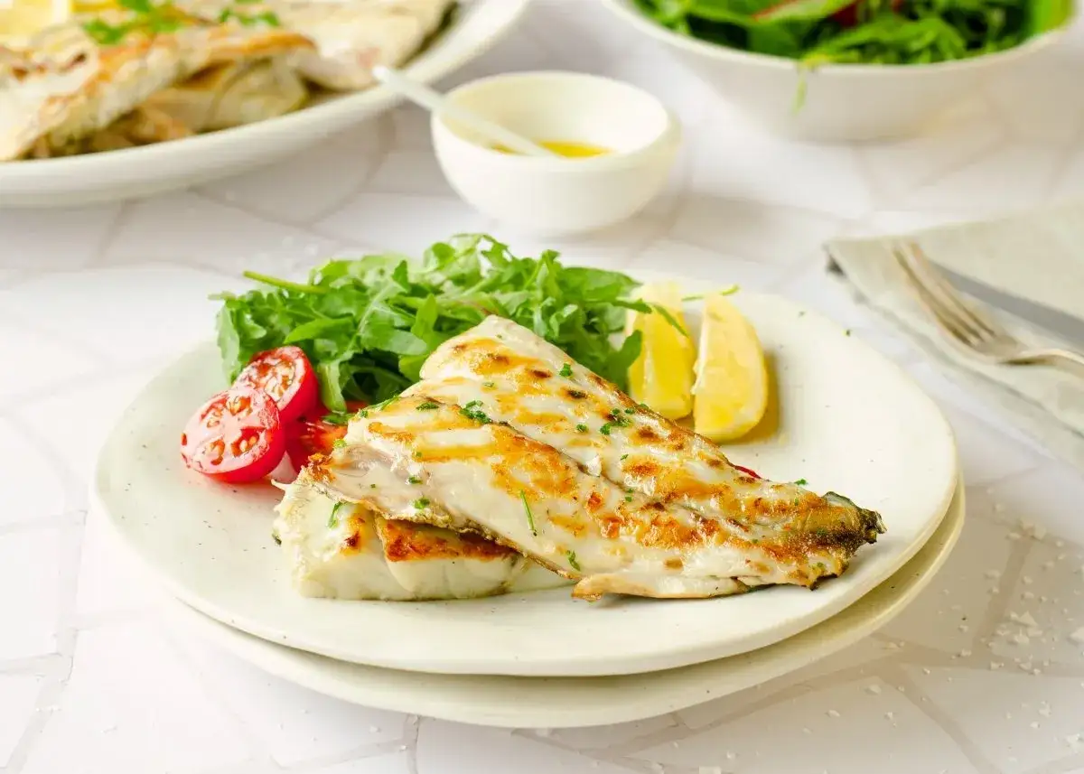 Deliciosa corvina a la plancha, servida con ensalada verde, tomates cherry y gajos de limón. Un plato ligero y sabroso.
