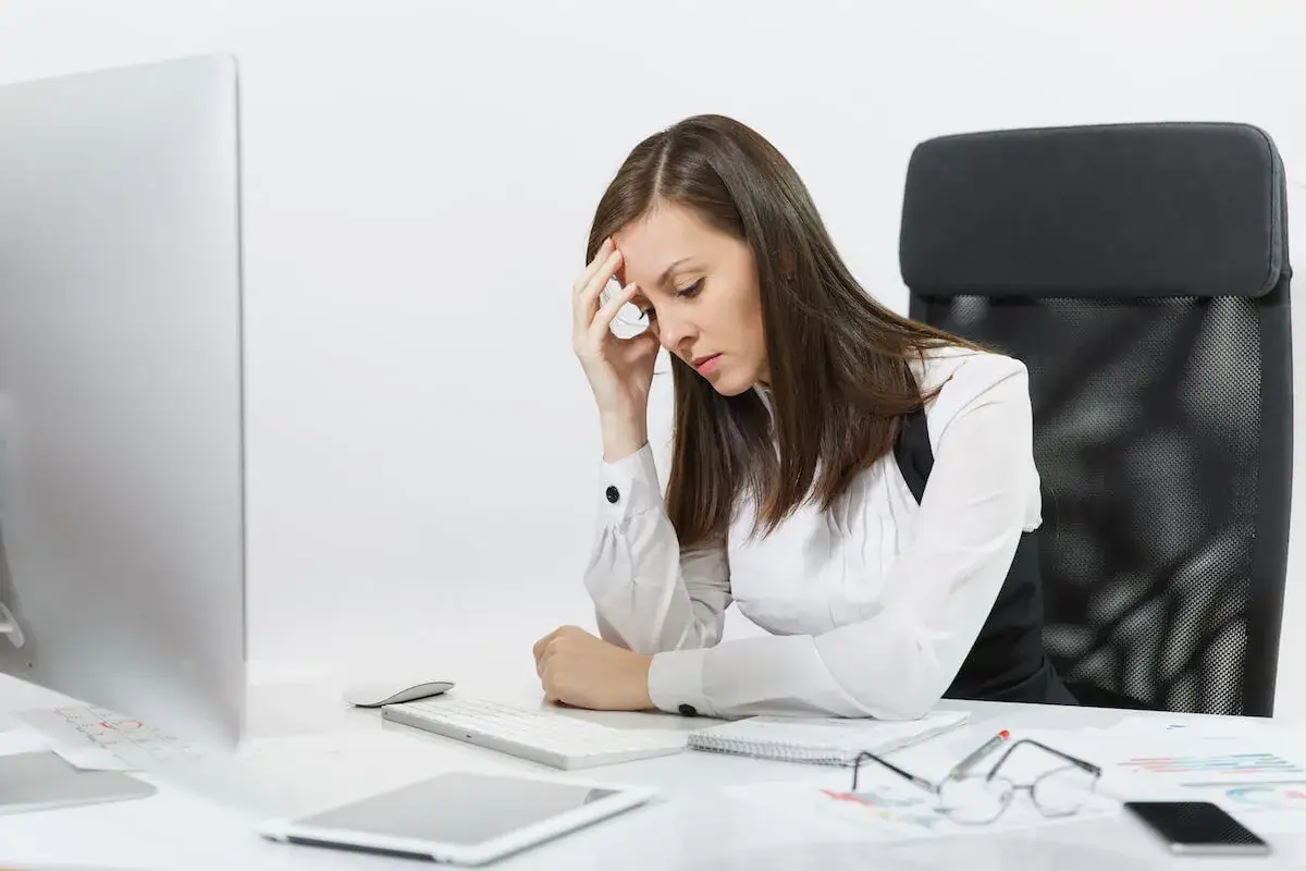 Zmartwiona kobieta przy biurku, myśląca o zawieszeniu działalności a ZUS.