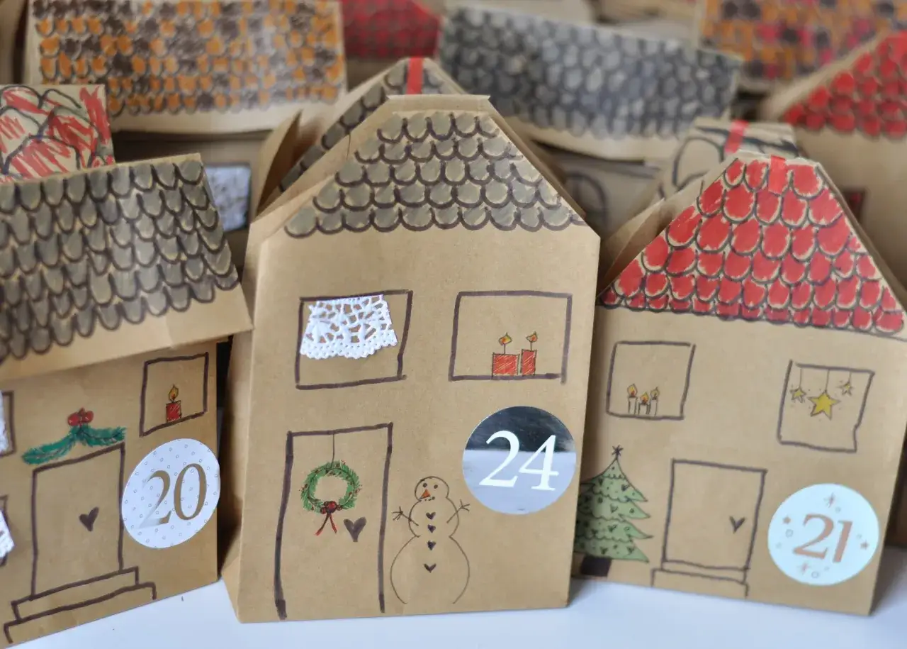 Kreative Adventskalender-Schule-Ideen: Selbstgebastelte Papierh&auml;user mit weihnachtlichen Motiven und Zahlen.
