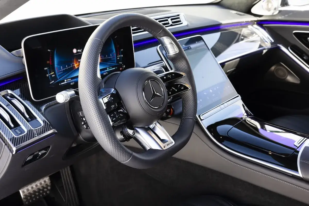 Wnętrze luksusowego Mercedesa S63 z nowoczesnym kokpitem, cyfrowymi zegarami i ekranem multimediów.