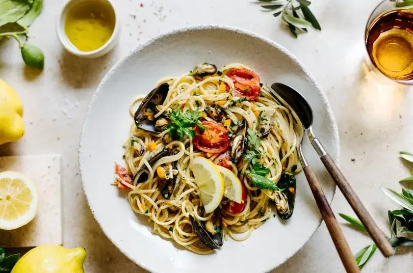 Pasta mit Muscheln professionell angerichtet mit Petersilie und Zitrone