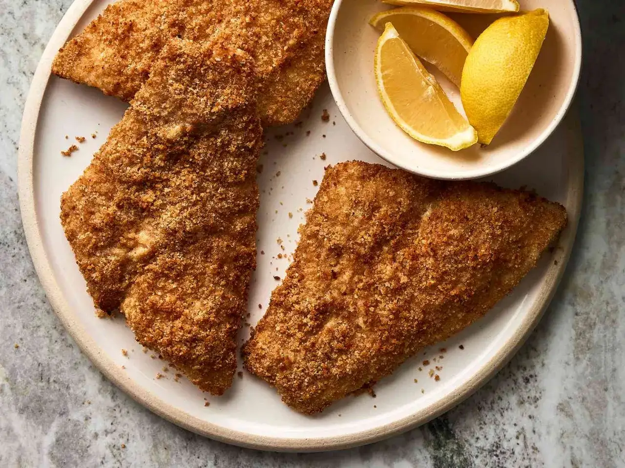 Chrupiąca ryba z airfryer na talerzu, podana z cytryną. Idealna na szybki obiad.