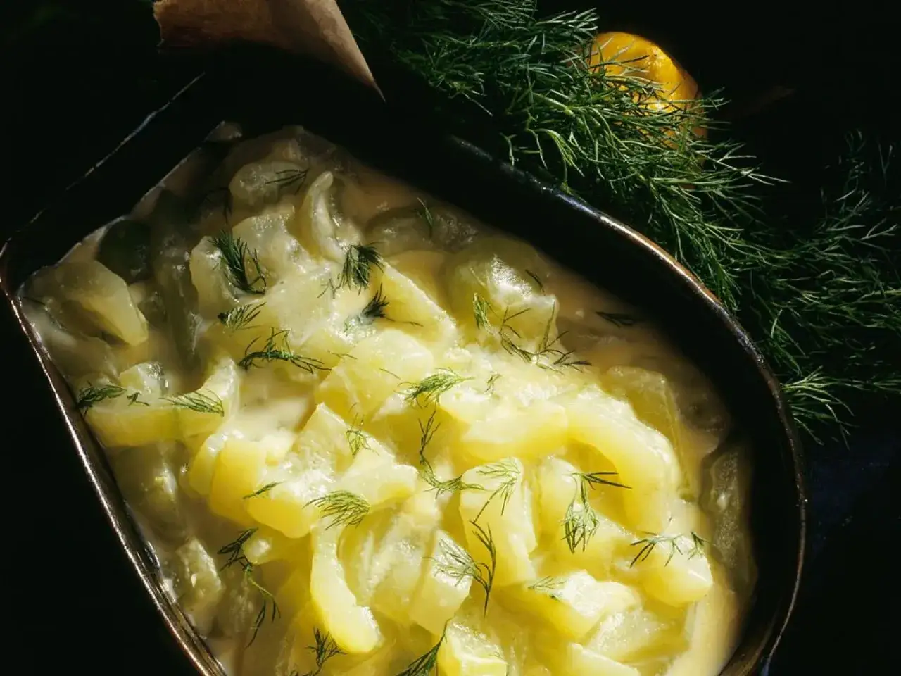 Schmorgurken in cremiger Soße, garniert mit Dill. So sehen sie aus, appetitlich und frisch, mit einem Hauch Zitrone im Hintergrund.