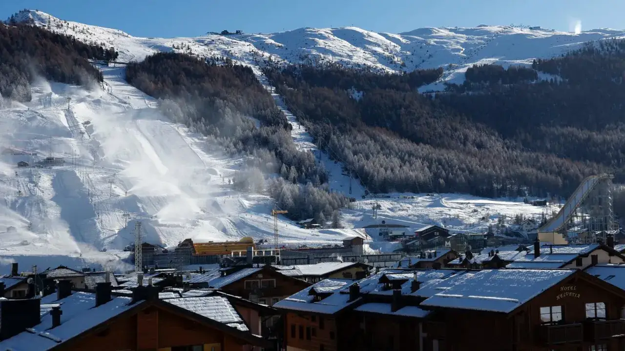 Vue panoramique de Livigno, Italie, avec des pistes de ski enneigées, des remontées mécaniques, des forêts d'épicéas et des chalets.