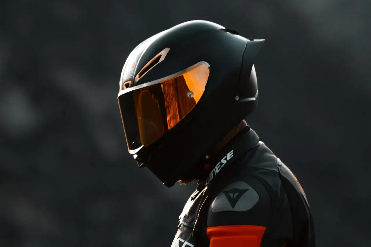 Casco nero lucido con visiera arancione riflettente, pronto per un giro in moto.