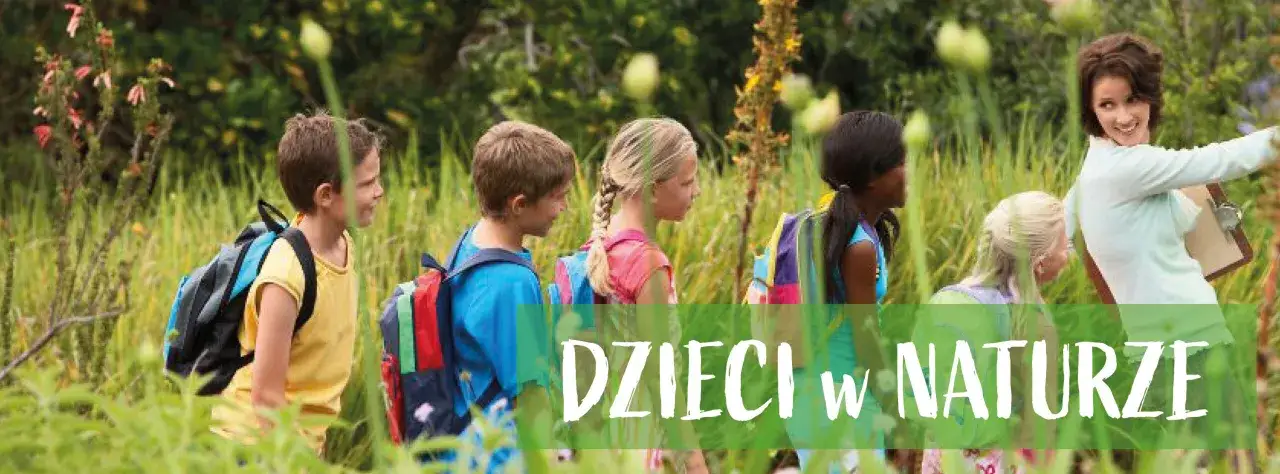 Dzieci z plecakami idą przez trawę, a nauczycielka pokazuje im coś ciekawego. To wspaniałe aktywności na świeżym powietrzu.