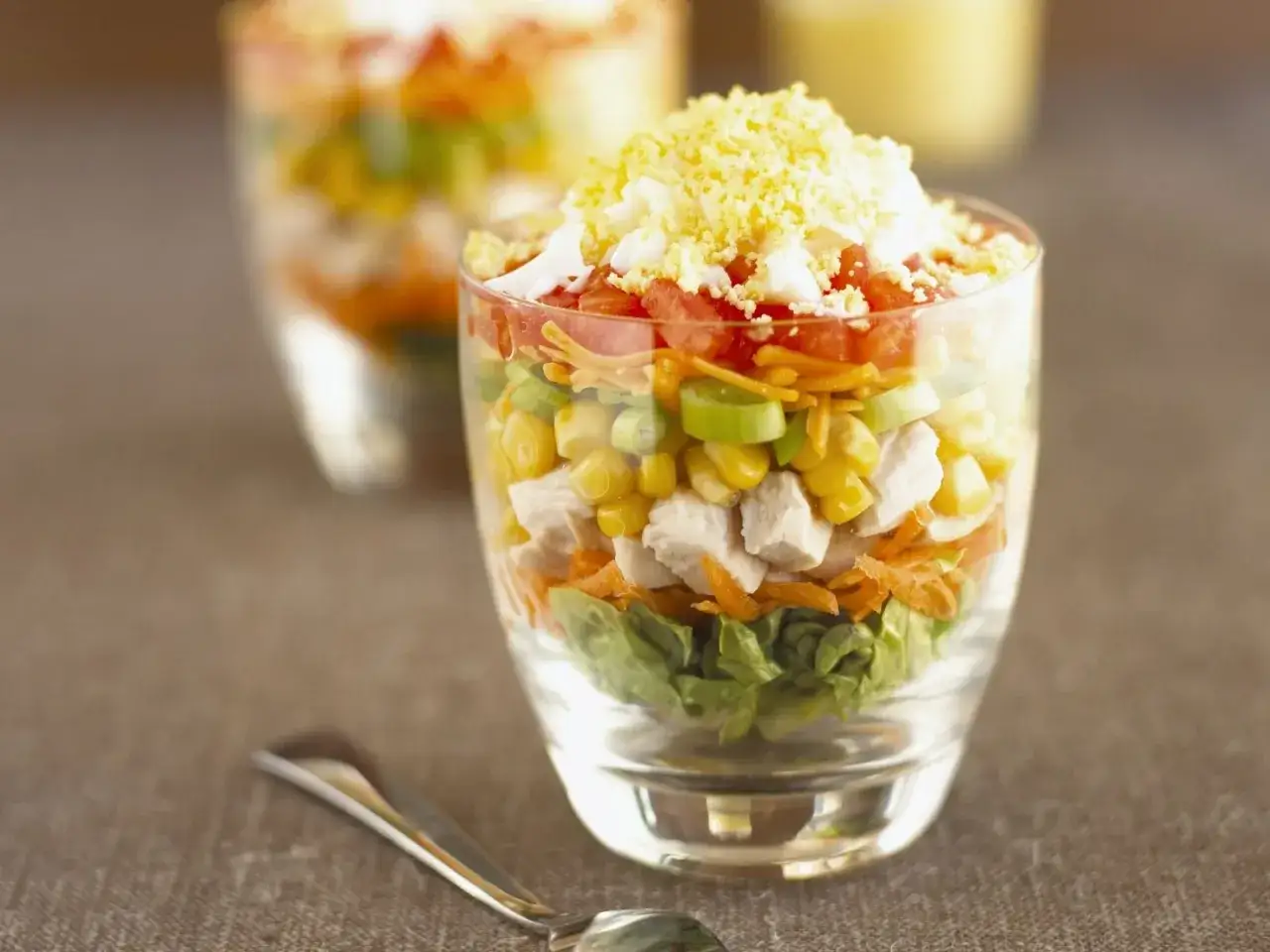 Schichtsalat rezept: Hähnchen, Mais, Tomaten und Ei in einem Glas geschichtet. Ein köstlicher und bunter Salat.