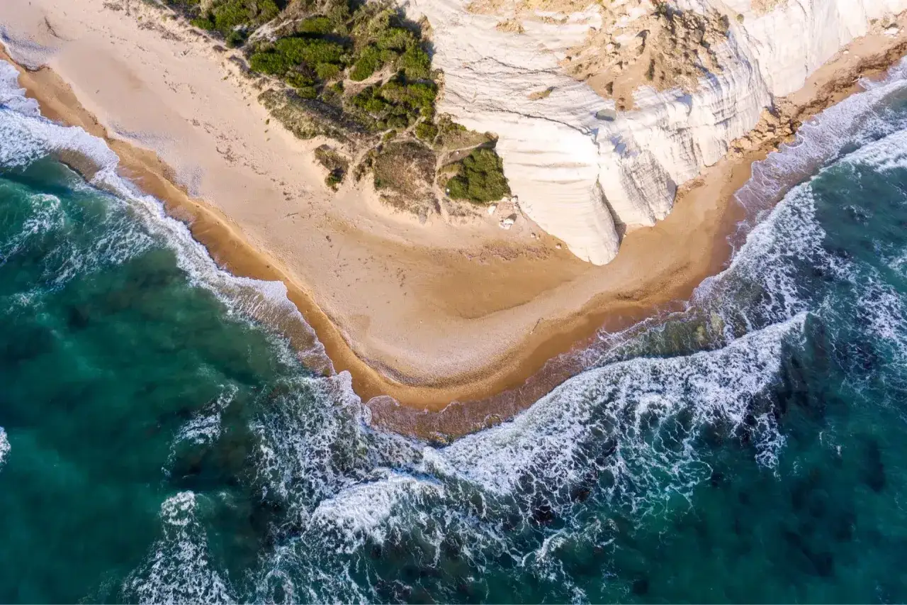 Spiaggia dorata e scogliere bianche a picco sul mare turchese, un angolo di paradiso tra le migliori spiagge in Sicilia.