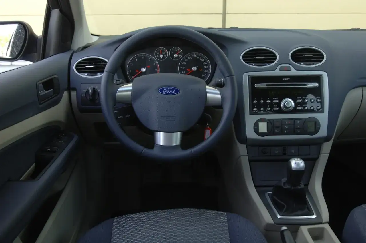 Wnętrze Ford Focus 2011: kierownica z logo Ford, deska rozdzielcza z radiem Sony, nawiewy i dźwignia zmiany biegów.