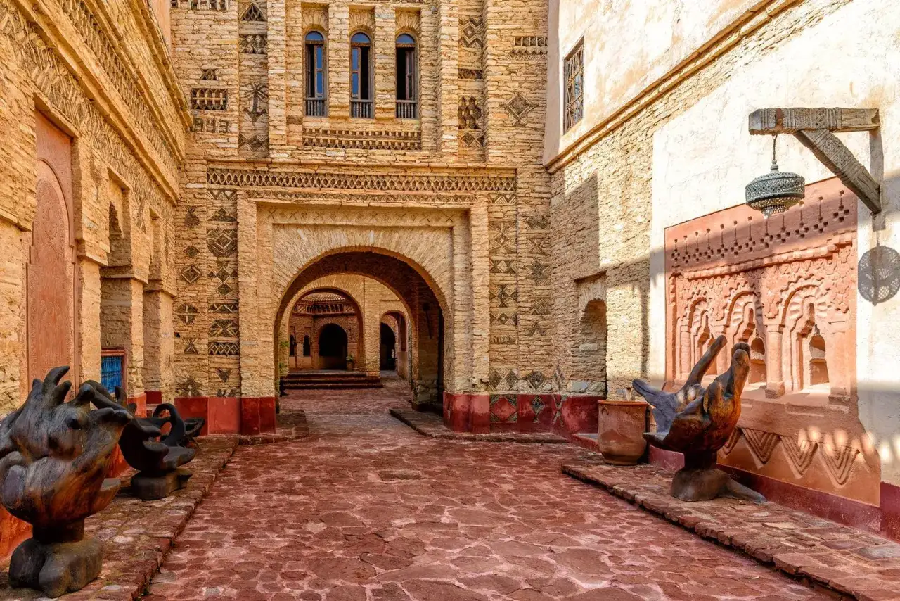 Ein Innenhof in der Agadir Altstadt mit B&ouml;gen, Steinmauern und roten Pflastersteinen.