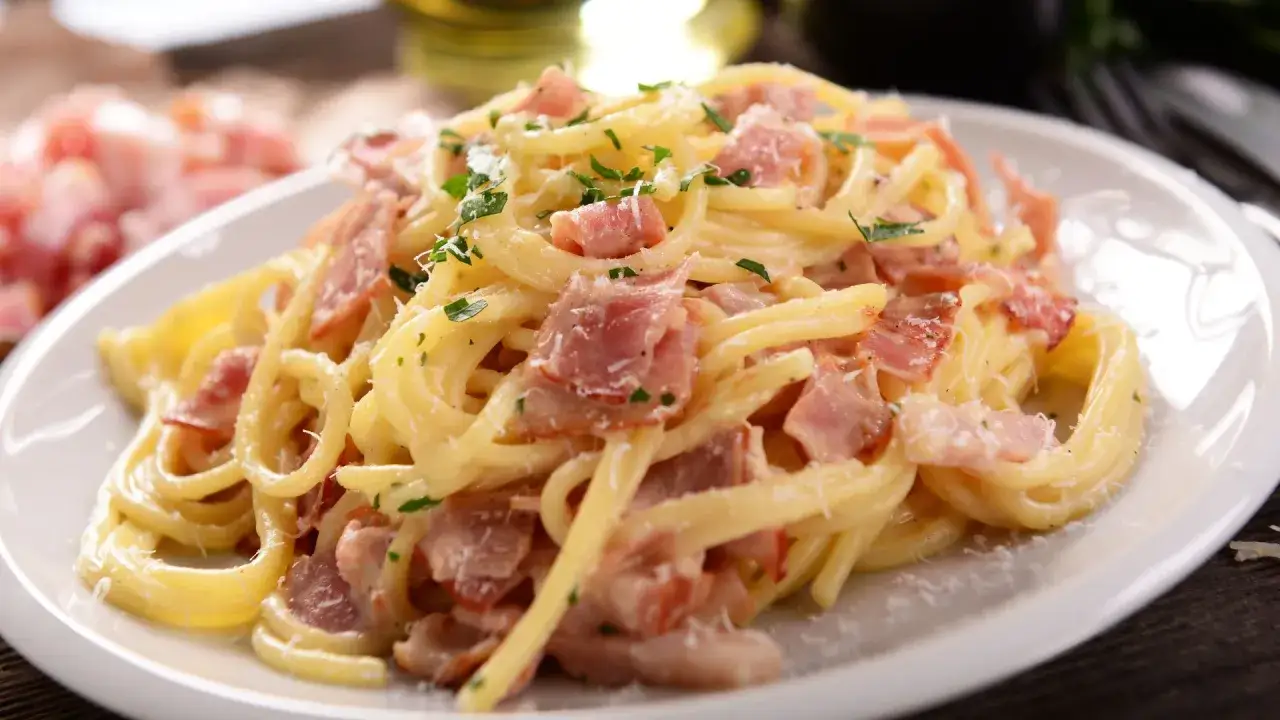 Pyszne spaghetti carbonara, jeden z klasycznych rodzajów makaronu, z kawałkami boczku i posypane parmezanem.