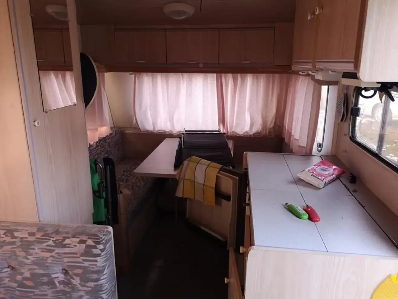 Wnętrze przyczepy Caravelair z rozkładaną kanapą, stołem i aneksem kuchennym.
