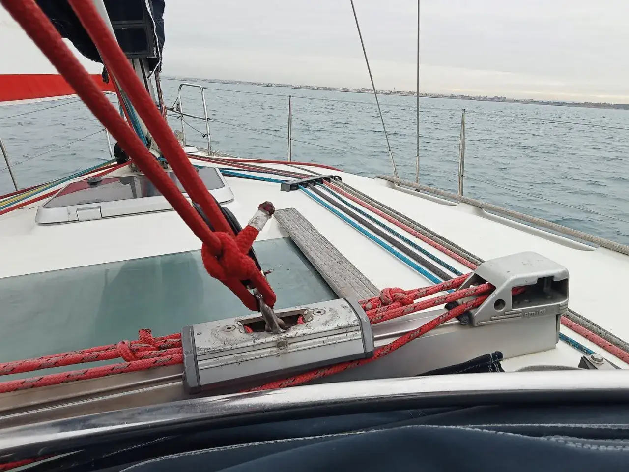 Un cavo per tendere le vele, rosso e robusto, è assicurato a un verricello su una barca a vela.