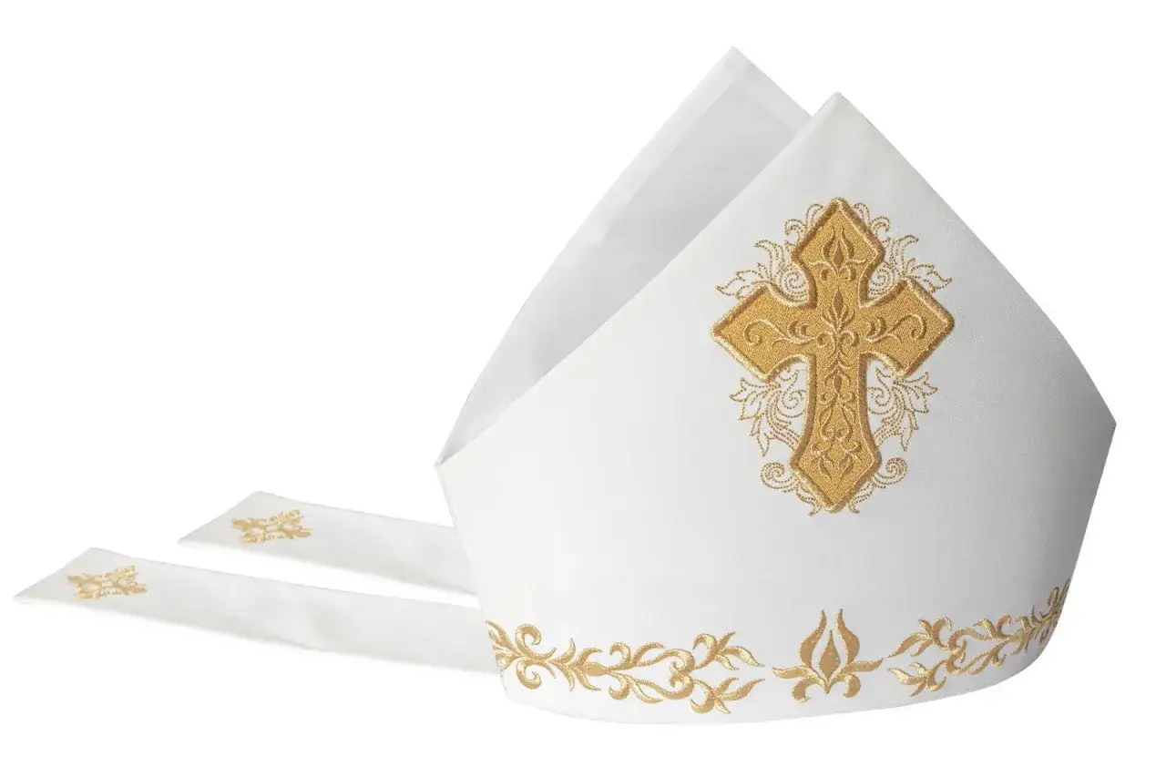 Biała mitra z haftowanym złotym krzyżem i ozdobnymi wstęgami, symbol godności duchownego.