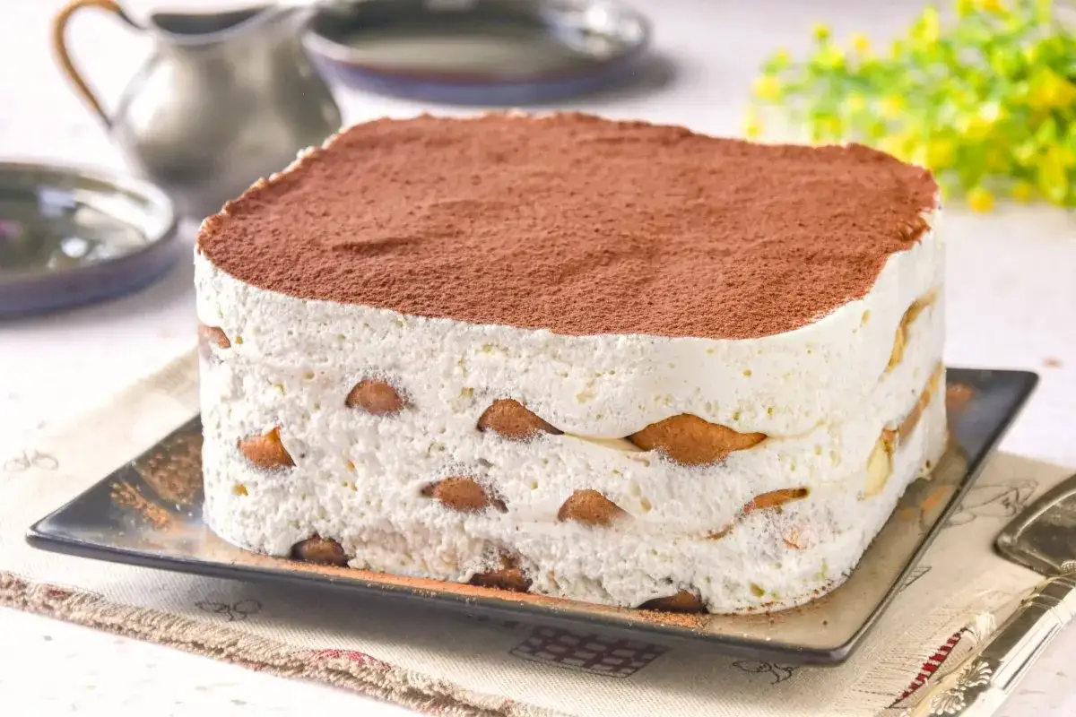 Tarta italiana mascarpone, un postre cremoso con capas de bizcochos y cacao espolvoreado.