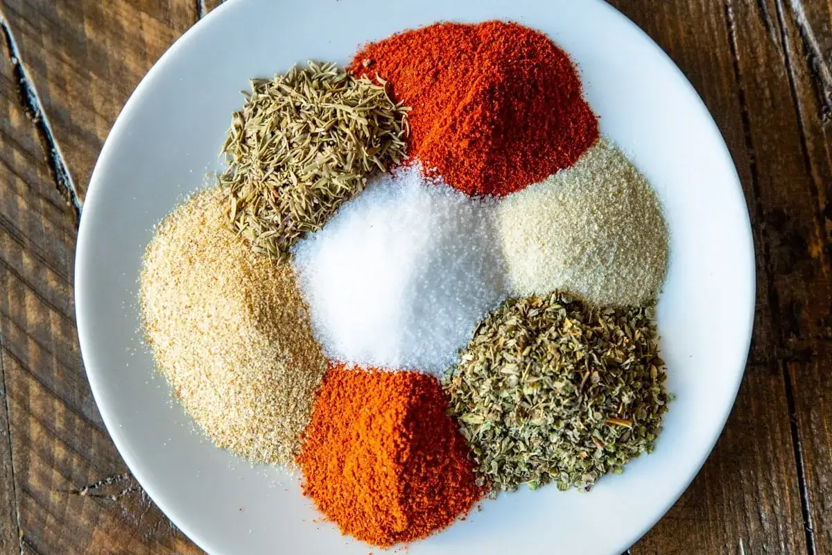 Kopczyki przypraw: papryka, czosnek, sól, tymianek, oregano i inne, tworzące mieszankę cajun.