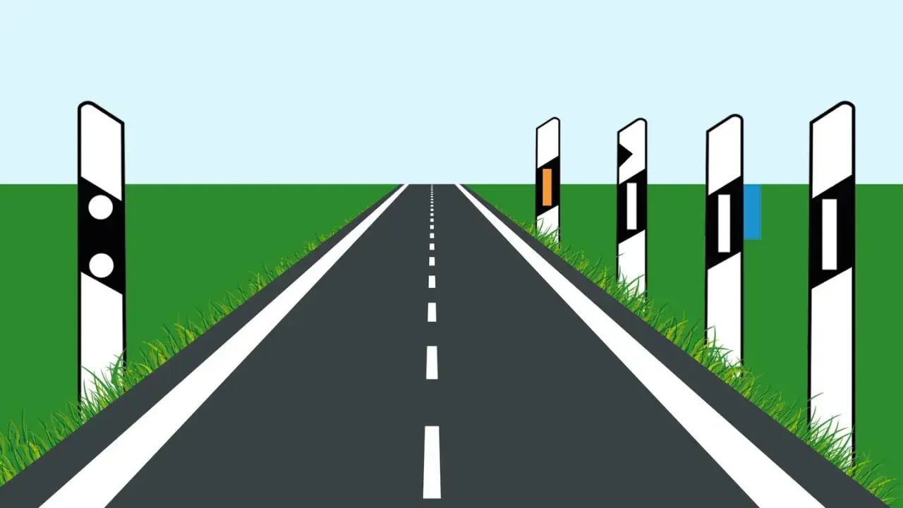 Gerade Stra&szlig;e mit Leitpfosten im Abstand von 25 m, die den Weg weisen. Gr&uuml;ne Wiesen und blauer Himmel.