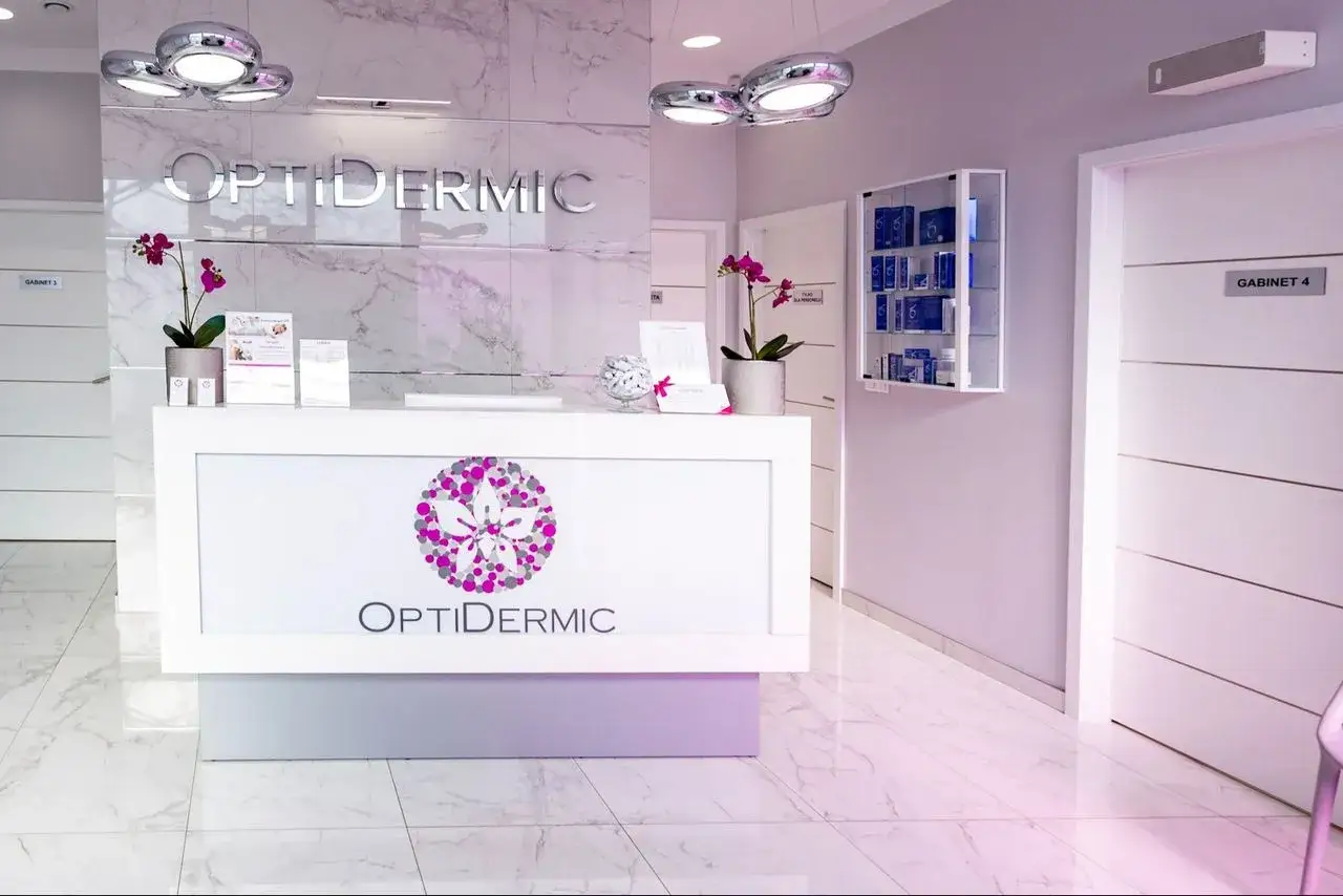 Recepcja kliniki OptiDermic z logo, kwiatem i gabinetami w tle.