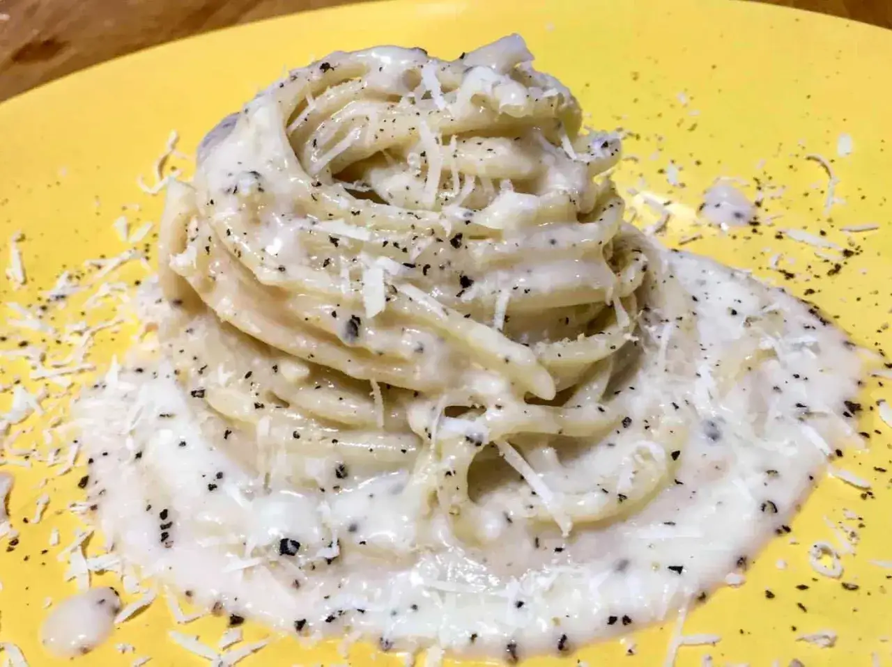 Un piatto di spaghetti cremosi, conditi con abbondante pecorino e pepe nero macinato fresco, un classico cacio e pepe.