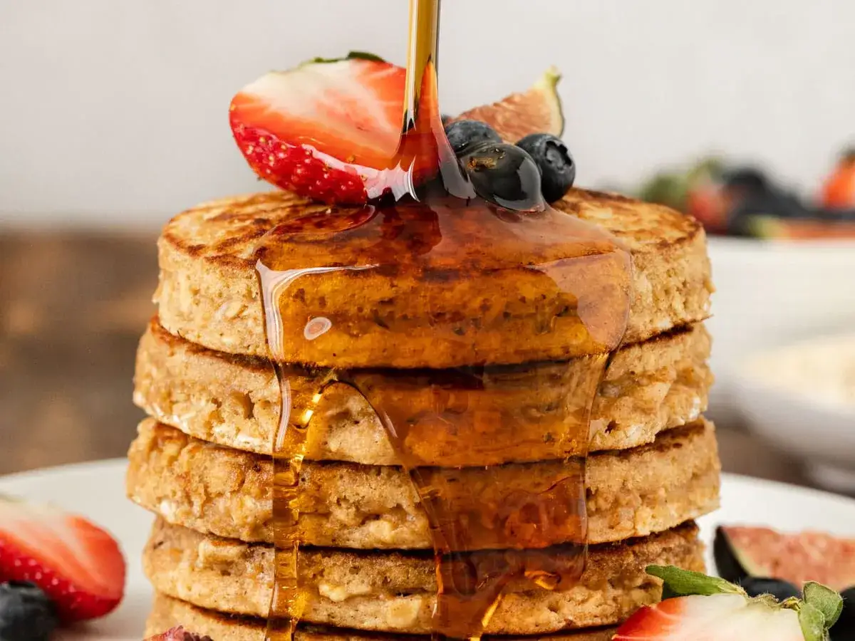 Pancakes con farina di avena, inzuppati di sciroppo d'acero e guarniti con fragole e mirtilli.