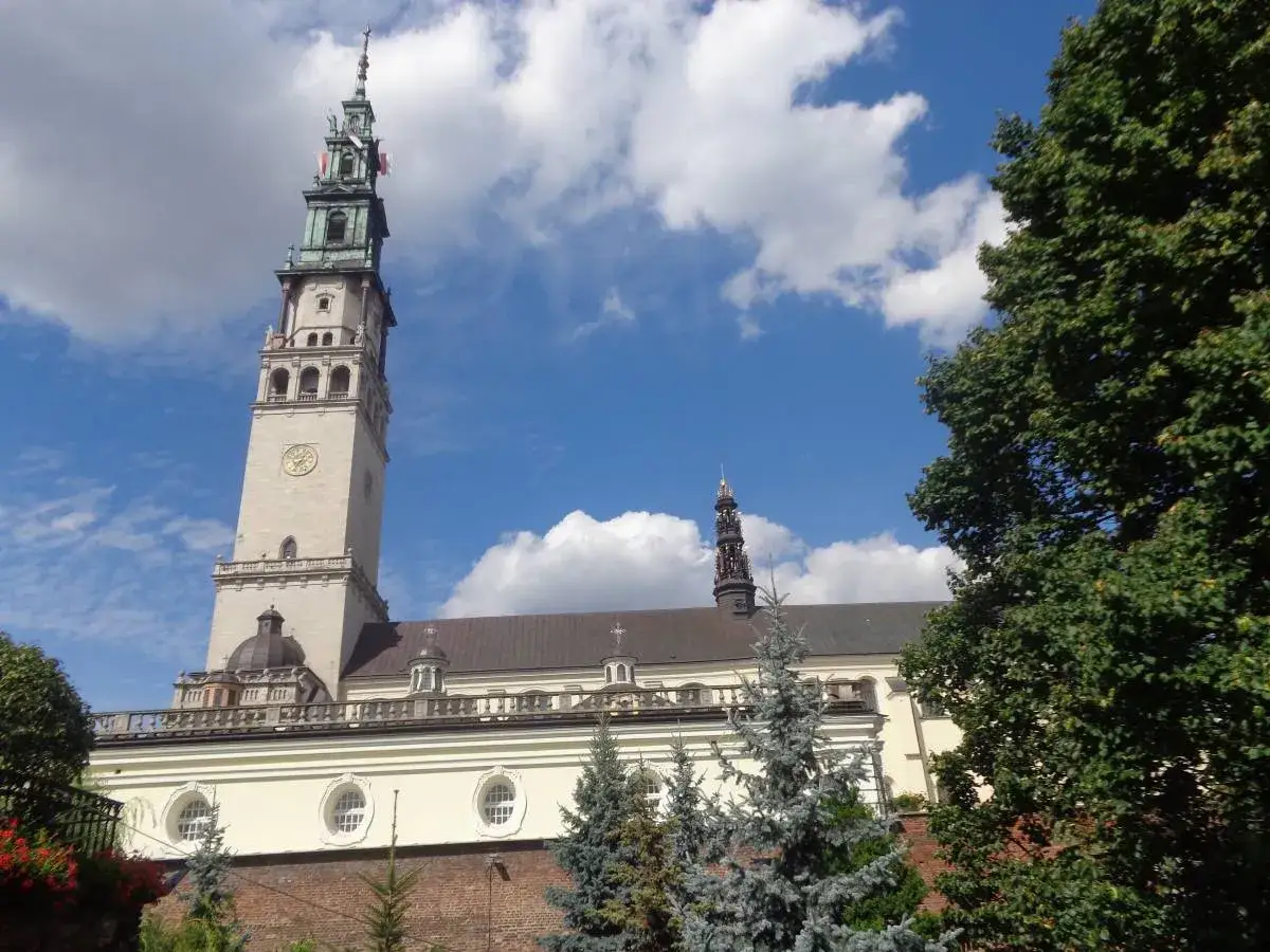 Jasna Góra w Częstochowie, majestatyczna wieża klasztoru na tle błękitnego nieba z chmurami.