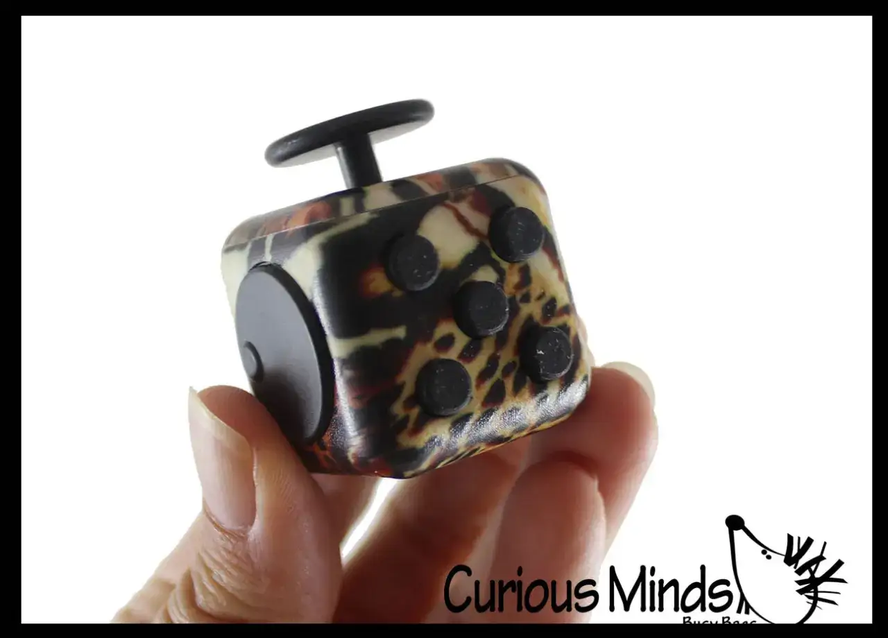 En hand h&aring;ller en fidget toys kub med leopardm&ouml;nster. Klickande knappar och en snurrande topp ger taktil stimulans.