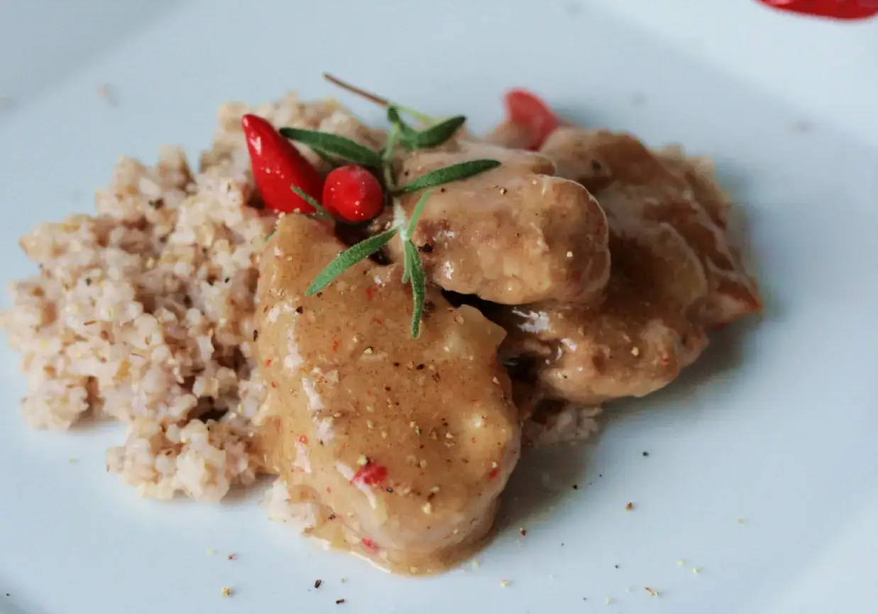 Polędwiczki wieprzowe w sosie podane z kaszą, ozdobione chili i rozmarynem. Pyszne danie, które zachwyci każdego smakosza.